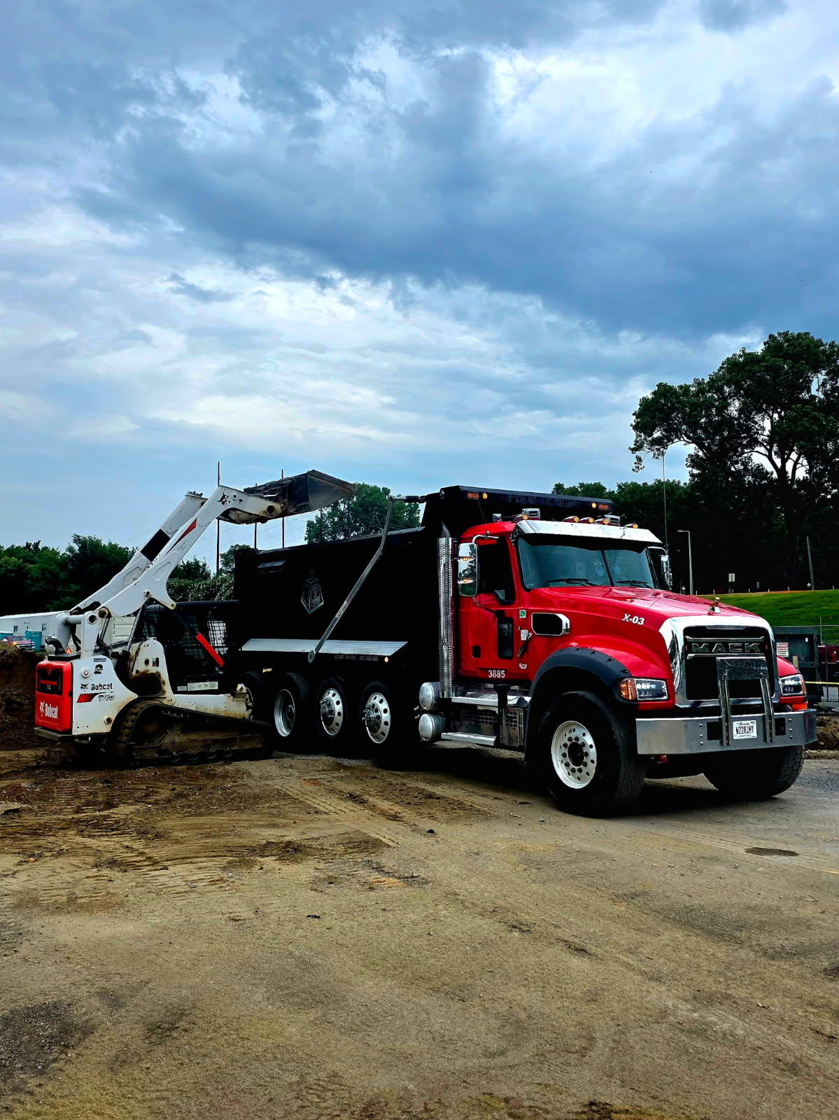Tare 2 Tons Xpress red quad-axle dump truck working alongside a loader